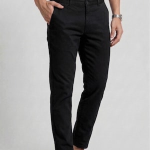 Può includere: Pantaloni neri dal design classico a gamba dritta. I pantaloni hanno una chiusura con bottoni e tasche. Il modello indossa una camicia bianca abbottonata e mocassini neri. I pantaloni sono realizzati in un tessuto resistente.