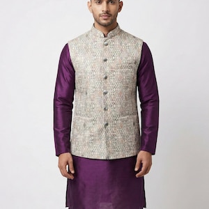 May include: A man wearing a purple kurta and white pants, paired with a patterned vest. The vest features a geometric design in neutral tones. The outfit is suitable for formal or festive occasions.