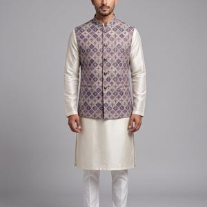 Op de afbeelding: Een formele outfit met een vest met patronen in paars en beige, gedragen over een crèmekleurig shirt met lange mouwen en een bijpassende broek. De outfit wordt gecompleteerd met schoenen met patronen, wat een samenhangende en stijlvolle look creëert.
