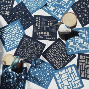 May include: A collection of indigo blue and white patterned fabric squares. The squares display diverse geometric designs, such as dots, lines, and cross patterns. A wooden bird figurine and a wood slice are also included, enhancing the natural theme.