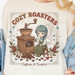 Könnte beinhalten: Cremefarbenes Sweatshirt mit detaillierter Illustration. Das Design zeigt eine Vintage-Kaffeemühle, eine Cartoonfigur, Kaffeebohnen und die Texte "COZY ROASTERS" und "Caffeine & Comfort". Das Kunstwerk ist mit floralen und himmlischen Elementen umrahmt.