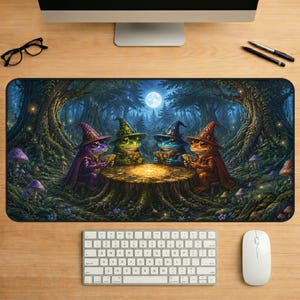 May include: A rectangular desk mat featuring a fantasy illustration of four frogs wearing pointed wizard hats and capes, sitting around a glowing tree stump in a dark forest at night. The scene includes tall trees, mushrooms, and a full moon.