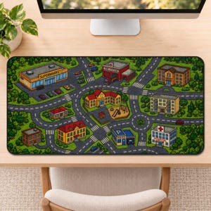 May include: A rectangular play mat featuring a colorful illustrated town map with roads, green trees, and various buildings including a supermarket, fire station, school, library, police station, and hospital, all set on a light-colored desk surface.
