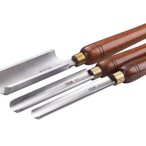 May include: A set of four wood turning chisels. The chisels have wooden handles with brass ferrules and polished steel blades. The blades are various shapes, including a gouge and two straight chisels. The tools are arranged on a white background.