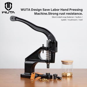 Peut inclure: Une presse manuelle noire WUTA avec un long levier pour installer des boutons-pression, des boutons, des œillets et des rivets. La machine dispose d'un mécanisme à ressort et comprend un bocal en verre rempli de composants métalliques dorés.