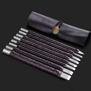 May include: A set of eight wood carving chisels with silver-colored metal tips and dark purple textured handles. The chisels are displayed with a dark purple leather tool roll with a decorative gold-colored button closure.