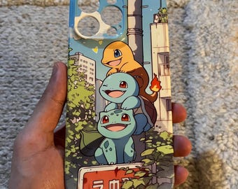 May include: A blue and white phone case featuring three cartoon characters stacked on top of each other. The case has a cityscape background with Japanese text at the bottom. The top edge of the case is light blue.