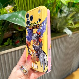 May include: Yellow and pink phone case featuring a Digimon Adventure graphic. The case has a cartoon illustration of a Digimon character with the text "DIGIMON ADVENTURE". The case is designed to protect the phone.
