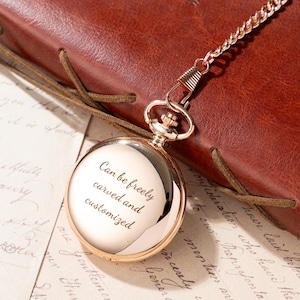 Puede incluir: Un reloj de bolsillo dorado con cadena, sobre una superficie de cuero marr&oacute;n. La esfera del reloj es reflectante, con el texto "Can be freely carved and customized" grabado. Un accesorio cl&aacute;sico.