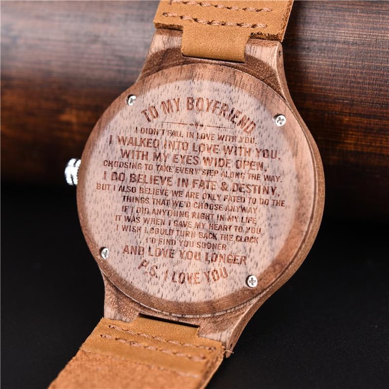 Puede incluir: Reloj de pulsera de madera con correa de cuero marr&oacute;n claro. La esfera del reloj est&aacute; grabada con un mensaje rom&aacute;ntico: "Para mi novio... Te amo". El reloj tiene un dise&ntilde;o cl&aacute;sico y un acabado de veta de madera natural.