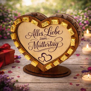 Könnte beinhalten: Ein herzförmiges Holzdisplay mit dem deutschen Text „Alles Liebe zum Muttertag“. Das Display enthält kleine, goldverpackte Pralinen. Das Herz steht auf einem Holzsockel, im Hintergrund Kerzen und eine Geschenkbox.