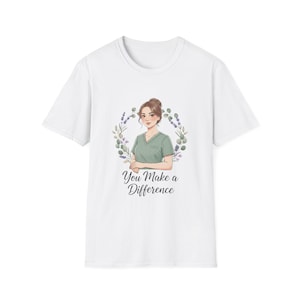 May include: White t-shirt featuring a graphic of a woman in a green scrub top, surrounded by a floral wreath. The text "You Make a Difference" is below the illustration. The shirt is made of a soft material.