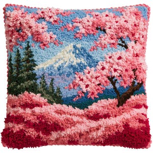 May include: A square throw pillow featuring a textured punch needle landscape design. The scene depicts a snow-capped mountain peak, dark green pine trees, and vibrant pink cherry blossom trees against a light blue sky, with a deep red foreground.