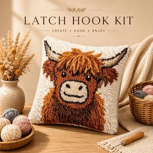 Peut inclure: Un kit de crochet à loquet comprenant un coussin carré avec un motif de vache Highland texturé dans des tons marron, crème et noir. Le texte LATCH HOOK KIT CREATE HOOK ENJOY est visible au-dessus. Inclut des pelotes et un crochet.