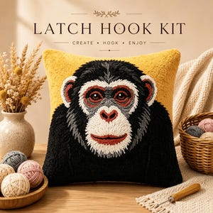 May include: A latch hook kit featuring a square pillow with a textured chimpanzee face design in black, white, and rust colors against a mustard yellow background. The text LATCH HOOK KIT CREATE HOOK ENJOY is printed above the pillow.