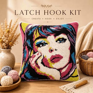 Peut inclure: Un coussin de kit de crochet à loquet carré présentant un portrait pop art vibrant d'une personne aux cheveux foncés, aux yeux bleus et aux lèvres roses. Le design utilise des couleurs vives dont le jaune, le magenta et le bleu. Le texte LATCH HOOK KIT CREATE HOOK ENJOY est visible.