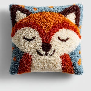 May include: A square decorative pillow featuring a smiling fox face. The fox has orange, white, and brown fur with closed eyes. The background is blue with orange dots. The pillow is made of a textured, tufted material.