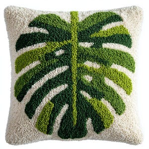 Peut inclure: Coussin carré avec un fond blanc cassé texturé et un grand motif de feuille de monstera verte. La feuille présente différentes nuances de vert, créant un effet texturé. Le coussin est de forme carrée, idéal pour ajouter une touche tropicale à n'importe quelle pièce.