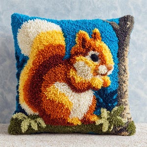 May include: Square throw pillow with a detailed, textured design of a squirrel. The squirrel has orange, yellow, and white fur, set against a blue background. The pillow features a tree branch and green leaves.