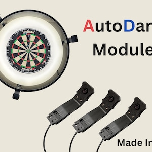 May include: A dartboard with a circular light and three black modules. The dartboard has red, green, and black sections. The text "AutoDarts Modules" is displayed in red and blue. The text "Made In UK" is also visible.