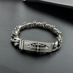 Puede incluir: Una taza de cerámica blanca con un asa negra y el texto "But First, Coffee" en negrita negra. La taza se encuentra sobre un fondo borroso, resaltando su diseño limpio.