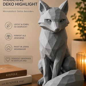 Könnte beinhalten: Eine graue Fuchsfigur mit einer geometrischen, facettierten Oberflächenstruktur. Der Fuchs sitzt in einer aufrechten Position mit dem Schwanz seitlich um den Körper gewickelt. Das Bild enthält den Text: MODERNE DEKO HIGHLIGHT, Minimalistisch.