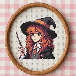 Puede incluir: Un retrato de punto de cruz de un personaje de una serie de fantasía, enmarcado en un aro de madera redondo. El personaje tiene el pelo rojo, gafas y un sombrero de bruja negro, sosteniendo una varita. El fondo es un patrón de cuadros rosas y blancos.