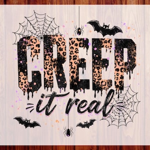 May include: A DTF transfer sheet featuring the text CREEP it real in a black and peach leopard print pattern with dripping effects. The design includes black spiderwebs, spiders, and bats, accented with small orange and purple paint splatters.