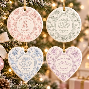 May include: Four ceramic ornaments with floral patterns and gold hanging strings. Two are circular and two are heart-shaped. They feature personalized text including names, the word Engaged, and dates: 06.14.2026, 08.24.2026, 04.19.2026, and 05.25.2026.