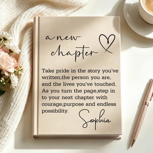 Puede incluir: Un libro de tapa dura beige con el texto impreso en negro 'a new chapter' junto a un icono de corazón, un párrafo inspirador y el nombre 'Sophia'. El libro está colocado junto a un bolígrafo de oro rosa, una tela de punto blanca y un café.
