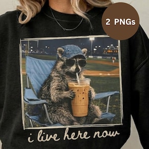 Peut inclure: Sweat-shirt noir avec un dessin d'un raton laveur portant des lunettes de soleil et une casquette en jean, buvant du café glacé assis dans une chaise bleue. Le texte "i live here now" est inclus.