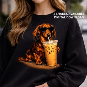 Peut inclure: Sweat-shirt noir avec un teckel marron portant des lunettes de soleil et buvant du caf&eacute; glac&eacute;. Le texte "2 SHADES AVAILABLE DIGITAL DOWNLOAD" est &eacute;galement pr&eacute;sent.