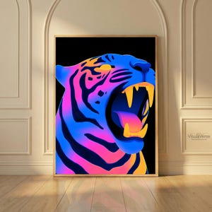 Puede incluir: Una impresión artística enmarcada que presenta una cabeza de tigre estilizada en colores vibrantes. La cara del tigre es una mezcla de azul, rosa y naranja, con colmillos amarillos y la boca abierta. La obra de arte está enmarcada en madera.