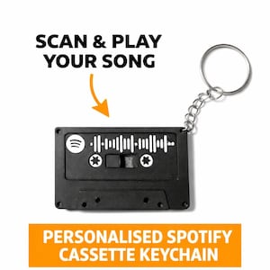 Peut inclure: Porte-clés en forme de cassette noire avec un code Spotify. Le porte-clés est doté d'un anneau et d'une chaîne argentés. Le texte sur l'image indique "SCAN & PLAY YOUR SONG" et "PERSONNALISÉ SPOTIFY CASSETTE KEYCHAIN".