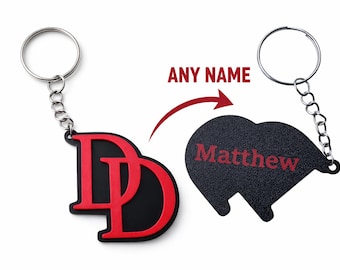 May include: Black and red personalized keychain with the name "Matthew" and the initials "DD". The keychain has a metal ring and chain. The text "ANY NAME" is above the heart-shaped keychain.
