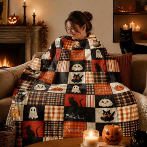 Könnte beinhalten: Eine Patchwork-Decke mit einem wiederkehrenden Muster aus schwarzen Katzen, weißen Geistern, orangefarbenen Kürbissen und Skeletten auf einem Hintergrund aus schwarzen, orangefarbenen und cremefarbenen Karofeldern. Das Wort Spooky steht in Schreibschrift.