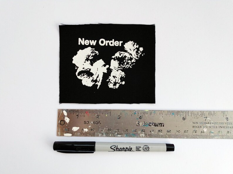 May include: Black fabric patch with white text that reads "New Order" and a white graphic design.