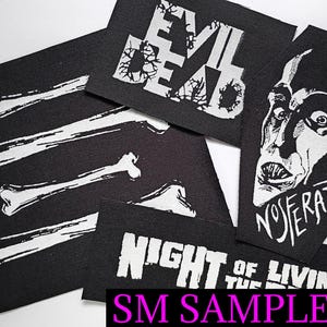 May include: Black fabric patches with white graphics. Designs include the words "EVIL DEAD", a Nosferatu face, bone illustrations, and the phrase "NIGHT OF THE LIVING". The text "SM SAMPLE #1" is also visible.
