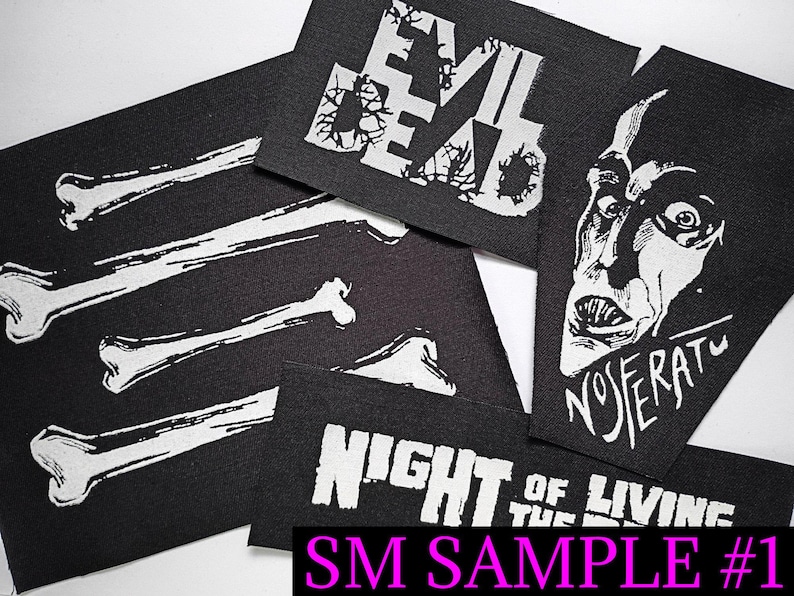 May include: Black fabric patches with white graphics. Designs include the words "EVIL DEAD", a Nosferatu face, bone illustrations, and the phrase "NIGHT OF THE LIVING". The text "SM SAMPLE #1" is also visible.