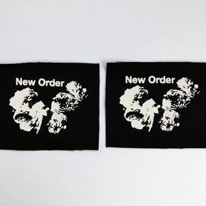 May include: Two black fabric patches with white text and a white graphic. The text on both patches reads "New Order".