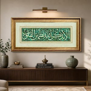 Può includere: Un'opera d'arte calligrafica islamica incorniciata con bordi dorati, con scrittura araba bianca su sfondo verde. L'opera è appesa sopra un mobile in legno scuro con oggetti decorativi.
