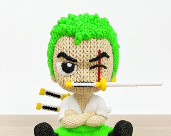 May include: A handmade figurine of a character with green hair, a scar, and a sword in its mouth. The figurine is wearing a white shirt, green pants, and black shoes. Two additional swords are attached to the back.