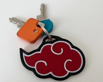 May include: A keychain featuring a red cloud design with white accents and a black border. The keychain is attached to a silver keyring with keys and an orange key cover.