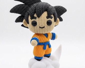 Può includere: Figurina all'uncinetto di un personaggio anime con capelli neri a punta, che indossa un completo arancione e blu, in piedi su una nuvola bianca. La figura ha un volto sorridente. Fatto a mano.