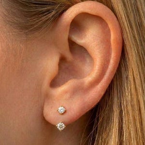 May include: A set of three ceramic mugs with a speckled, matte finish. Each mug features a different color: light blue, cream, and gray. The mugs have a simple, modern design with a rounded shape and a comfortable handle.