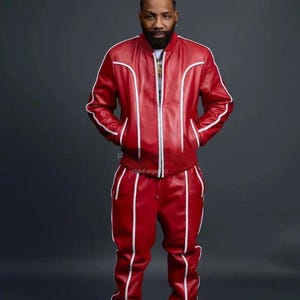 May include: Red leather tracksuit with white piping. The jacket features a zip, and the trousers have a drawstring. This striking outfit is a bold fashion statement.