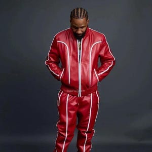 May include: A red leather tracksuit with white piping. The jacket has a zip closure and pockets. The trousers have a straight leg design. The text "HideForgCO" is visible on the jacket.