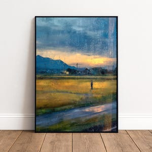 Può includere: Stampa artistica incorniciata raffigurante un paesaggio rurale al tramonto. L'opera presenta un campo di colture dorate, una strada e una figura in lontananza. Una catena montuosa è visibile sullo sfondo sotto un cielo nuvoloso. La stampa è in una cornice nera.