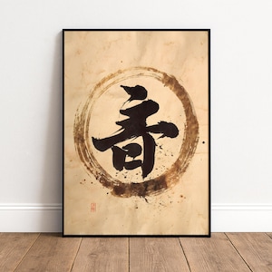 May include: Black framed art print featuring Japanese calligraphy. The artwork displays a bold black character within a circular brushstroke design on a textured, sepia-toned background. A small red stamp is visible in the lower left corner.