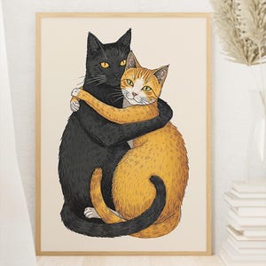 Op de afbeelding: Een ingelijste kunstdruk met twee knuffelende katten. Eén kat is zwart met gele ogen, de andere is oranje en wit met groene ogen. Het kunstwerk staat tegen een crèmekleurige achtergrond, in een houten lijst.